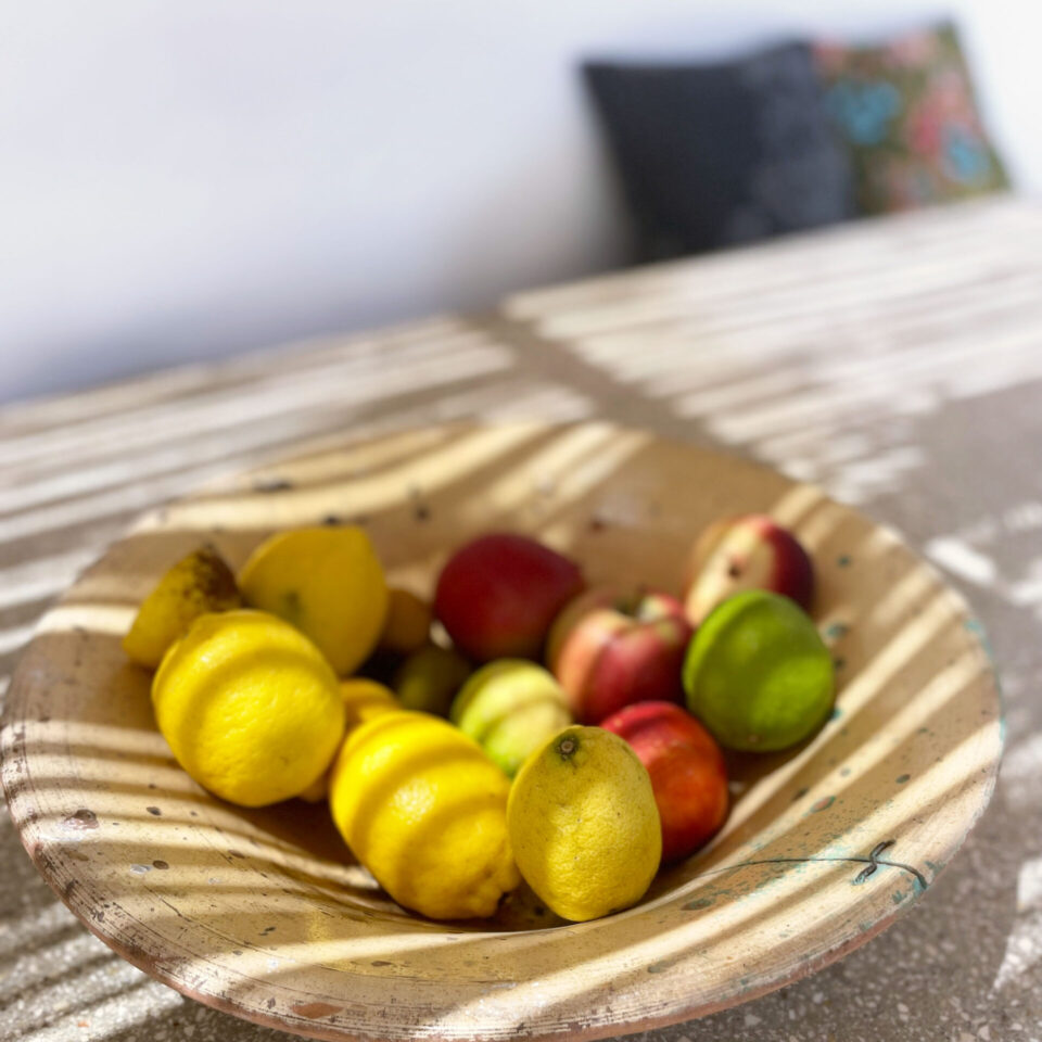 A fruit bowl on the concrete table in the shade of the pergola